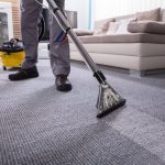 Low Section Of A Person Cleaning The Carpet With Vacuum Cleaner In Living Room